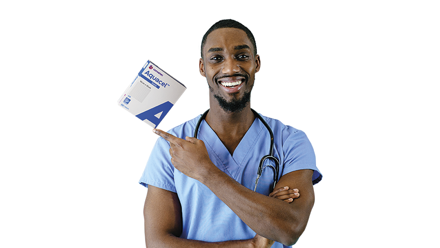 A smiling male healthcare professional in blue scrubs pointing at Aquacel Extra wound dressing packages.